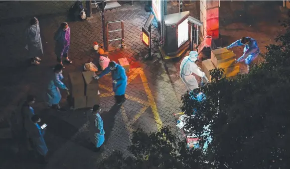  ?? ?? Workers shift supplies at the entrance of a locked-down residentia­l area in Shanghai. Picture: AFP