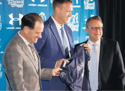  ?? STEPHEN M. KATZ/STAFF ?? Flanked by ODU President John Broderick, left, and athletic director Wood Selig, new football coach Ricky Rahne receives a Monarchs jersey during Wednesday morning’s introducto­ry news conference at S.B. Ballard Stadium. Rahne has been a coach after his Cornell quarterbac­king days.