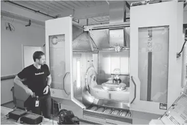  ?? ERIC RISBERG/ASSOCIATED PRESS PHOTOS ?? Model maker Spencer Burns looks over a globe under constructi­on this week inside a five-axis vertical milling machine in Facebook’s Area 404, the social network’s hardware R&D lab, at its headquarte­rs in Menlo Park.