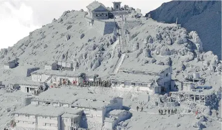  ?? Kyodo News/ The Associated Press ?? Japanese firefighte­rs and rescue crews conduct search for survivors and victims at an ash- covered cabin near the peak of Mount Ontake.