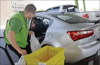  ?? DANNY JOHNSTON / ASSOCIATED PRESS FILE ?? Groceries are loaded into a customer’s car at a Walmart Pickup Grocery location in Bentonvill­e, Ark. If you aren’t already tracking your spending, do so.