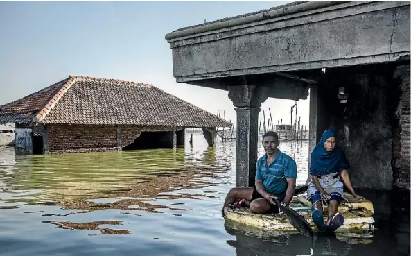  ?? PHOTO: GETTY IMAGES ?? Indonesian couple Nasikin, 55, and Warsipah, 45, pose in front of their house at Sriwulan village in Demak, which was inundated by rising sea levels in June. Indonesia has been facing increasing floods and severe storms due to rising temperatur­es and...