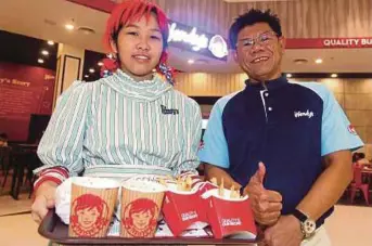  ??  ?? SAW (kanan) bersama pelayan menunjukka­n menu burger terkenal Wendy's yang baru dibuka di Paradigm Mall Johor Bahru.