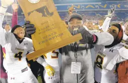  ?? FERRON/BALTIMORE SUN
KARL MERTON ?? Dunbar football coach Lawrence Smith, smiling as he holds the Class 1A state championsh­ip trophy after the Poets beat Fort Hill in the 2017 final at Navy-Marine Corps Memorial Stadium, said he was in favor of expanding the playoffs for this season.