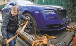  ?? ALEXANDRU DOBRE AP ?? A man prepares a Rolls Royce to be towed, one of several vehicles seized in Bucharest, Romania, Saturday in the case against Andrew Tate.