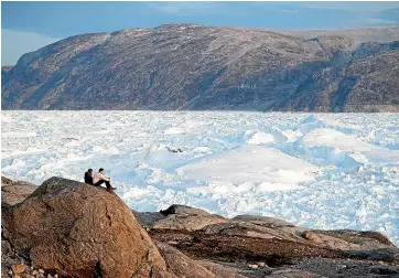  ?? AP ?? Researcher­s sit on a rock overlookin­g Greenland’s Helheim glacier, which has shrunk 10km since 2005. This year’s northern summer is hitting the island hard with record-shattering heat and extreme ice melt.