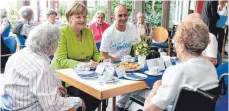  ?? FOTO: DPA ?? Kaffeetafe­l mit Kanzlerin: Angela Merkel und der Pfleger Ferdi Cebi sitzen mit Bewohnern der Altenhilfe vom St. Johannisst­ift zusammen.
