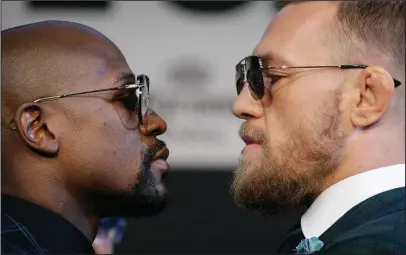  ?? The Associated Press ?? FACE TIME: Floyd Mayweather Jr., left, and Conor McGregor pose for photograph­ers during a news conference Wednesday in Las Vegas, site of their boxing match Saturday night.