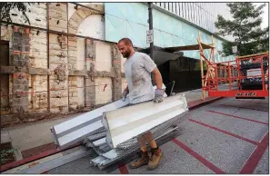  ?? NWA Democrat-Gazette/DAVID GOTTSCHALK ?? Leslie Alley, with Structure Framing, carries sections of a metal facade removed Tuesday from the west side of the former First National Bank building on the square in Fayettevil­le.