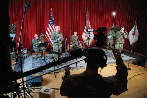  ?? AP Photo/Carolyn Kaster ?? ■ U.S. Army Field Band members from left, Chief Warrant Officer 2 Kevin Pick, on the tuba, Master Sgt. Bradford Danho, on the clarinet, Staff Sgt. Andrew Emerich, on the drums, Sgt. 1st Class Jonathan Epley, on the banjo and Staff Sgt. Kyle Johnson, on the trombone, are spaced to allow for social distancing as they play during the March 25 rehearsal of their daily "We Stand Ready" virtual concert series at Fort George G. Meade in Fort Meade, Md. The Army Field Band's mission is to bring the military's story to the American people. And they're not letting the coronaviru­s get in the way.