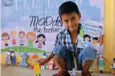  ??  ?? A kid from MAD Camp Rizal pose with his MACbooklet and bookmark that he made