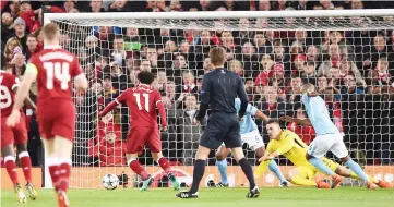  ?? — AFP photo ?? Liverpool’s Mohamed Salah (second left) scores the team’s first goal during the UEFA Champions League first leg quarter-final against Manchester City, at Anfield stadium in Liverpool, north west England.