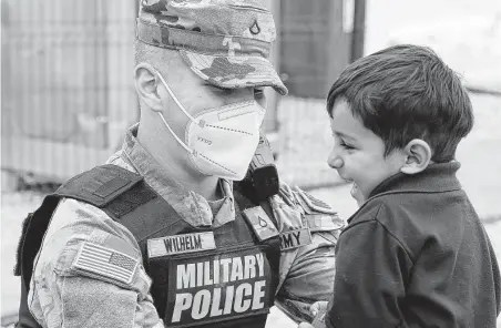  ?? Capt. Mikel Arcovitch / Associated Press ?? Army Pfc. Brandon Wilhelm with Task Force Ever Vigilant plays with a young Afghan evacuee on Oct. 1 at Camp Liya, Kosovo.