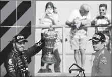  ?? AFP ?? Lewis Hamilton celebrates with the British Grand Prix trophy as runner-up Charles Leclerc looks on at Silverston­e, England on Sunday. Hamilton’s victory cut Max Verstappen’s lead in the Formula 1 driver standings to eight points.