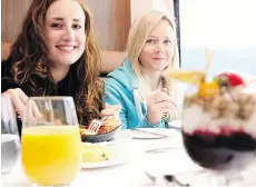  ??  ?? Journalist Laura Mitchell, right, was on a mission to see a grizzly bear while riding on the Rocky Mountainee­r. Here she enjoys breakfast aboard the train with fellow U.K. journalist Hollie-Rae Brader.