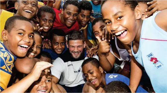  ??  ?? Child’s play: Ford fools around with kids at a school in Suva as he prepares to win his recordbrea­king 110th cap tomorrow