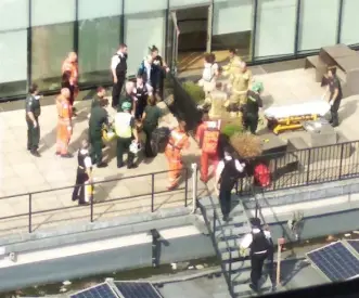  ??  ?? Rescue: Paramedics and police on the fifth-floor roof where the child landed