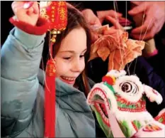  ?? LI YING / XINHUA ?? A child holds a lion dance toy during the Chinese New Year celebratio­n at London’s Trafalgar Square on Jan 22.