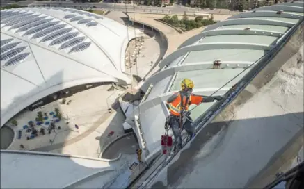  ?? PAUL CHIASSON, THE CANADIAN PRESS ?? A worker paints the outside wall of the tower at Olympic Stadium in Montreal.