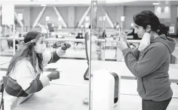  ?? MAX WHITTAKER/THE NEW YORK TIMES ?? Safa Sareshwala, left, helps a student take a saliva sample Jan. 25 at a coronaviru­s testing site for University of California, Davis students and faculty. Schools are trying to stop infection rates from soaring again.