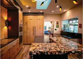  ?? Kaylee Greenlee Beal/contributo­r ?? The kitchen’s centerpiec­e is the terrazzo-topped island, which stands out against black countertop­s. A skylight and window over the sink bring in natural light.