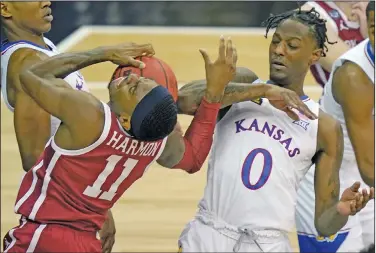  ?? Associated Press ?? Physical play: Oklahoma guard De'Vion Harmon (11) is called for traveling while covered by Kansas guard Marcus Garrett (0) during the first half of an NCAA college basketball game Thursday in the quarterfin­al round of the Big 12 men's tournament in Kansas City, Mo.