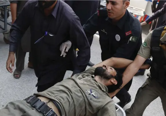  ?? MOHAMMAD SAJJAD/ THE ASSOCIATED PRESS ?? Pakistani security officials rush their colleague to a local hospital in Peshawar, Pakistan, after the Taliban launched a brazen assault on a military base on Friday.