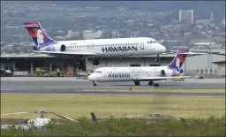  ?? The Maui News MATTHEW THAYER photo ?? A Hawaiian Airlines jet lands at Kahului Airport on March 31 as another is getting ready to take off. Maui County Mayor Michael Victorino has asked Gov. David Ige to reinstate the interislan­d travel quarantine in the wake of the spread of COVID-19 cases on Oahu.