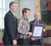  ?? ANDREW VAUGHAN / THE CANADIAN PRESS ?? Premier Stephen McNeil, left, and advisory board chair Hugh Laurence, flank Travis Wolfe, a Nova Scotia Medal of Bravery recipient, at Province House in Halifax.