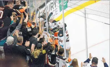  ?? The Ducks ?? PLAYERS for the Gulls, a Ducks minor league affiliate, celebrate a goal against the Reign — a farm team for the Kings — in an exhibition game this week. Fans at Honda Center show their support.