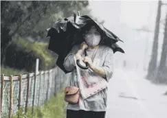  ??  ?? 0 A woman braves the rain as the typhoon nears in Kagoshima