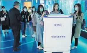  ?? YU JIE / FOR CHINA DAILY ?? Visitors gather around a 5G-enabled medical device at the display center of the Lin-gang Special Area of China (Shanghai) Pilot Free Trade Zone.