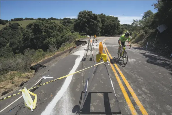  ?? Paul Kuroda / Special to The Chronicle ?? A profession­al bicyclist rides along damaged Redwood Road in Castro Valley. Cars aren’t allowed on this part of Redwood Road that is near Lake Chabot.