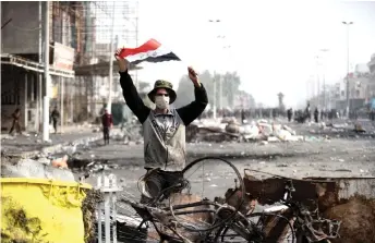  ?? — AFP photo ?? An Iraqi demonstrat­or carries the national flag in the southern Iraqi Shiite holy city of Najaf.