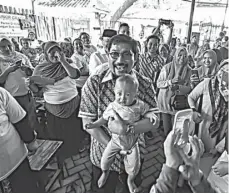  ?? TIMSES MA FOR JAWA POS ?? DEKATI WARGA: Machfud menggendon­g bayi dalam acara di Sukolilo.