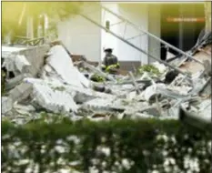  ?? BRYNN ANDERSON — THE ASSOCIATED PRESS ?? An official walks near debris after an explosion on Saturday in Plantation, Fla. The explosion happened Saturday morning at a shopping center in Plantation, west of Fort Lauderdale in Broward County. The blast sent large pieces of debris about 100 yards (about 91 meters) across the street.