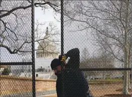  ?? Kevin Dietsch Getty Images ?? A WORKER helps install fencing around the U.S. Capitol on Sunday. President Biden is scheduled to deliver his State of the Union address on Tuesday night.