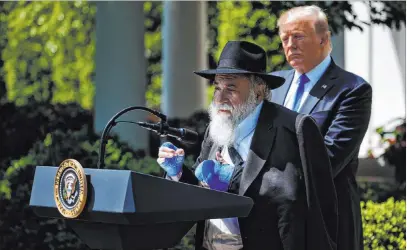  ?? Evan Vucci The Associated Press ?? President Donald Trump looks on as Rabbi Yisroel Goldstein, survivor of the Poway, Calif., synagogue shooting, speaks Thursday during a National Day of Prayer event in the Rose Garden of the White House.