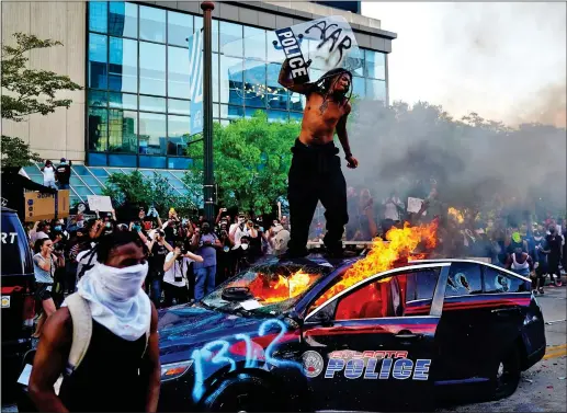  ??  ?? FURY: A man stands on top of a burning police car during a protest in Atlanta, Georgia – one of many held in the wake of George Floyd’s death