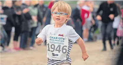  ??  ?? Above, a youngster in the junior race. Right: Elliot Crumb, 4, from Crail, with Kenny Brown.