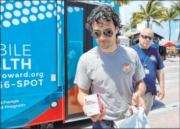  ?? Freida Frisaro The Associated Press ?? Huston Ochoa, a clinical counselor for The SPOT, hands out samples of Narcan, which can reduce opioid overdoses, to spring breakers last month in Fort Lauderdale, Fla.