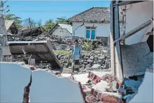  ?? FAUZY CHANIAGO THE ASSOCIATED PRESS ?? A man inspects a village destroyed by a strong earthquake in Kayangan, Lombok Island, Indonesia, Monday.