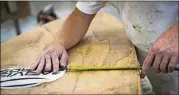  ??  ?? Ivan Scott takes a measuremen­t to center the Jarvis Boards logo on a paddleboar­d at the company’s workshop July 25. Scott lost part of his right middle finger to a table saw while constructi­ng houses.