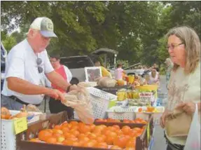  ??  ?? Shoppers can purchase tomatoes and other vegetables during growing season at local farmers market.