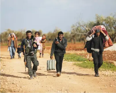  ??  ?? DISPLACED PEOPLE walk with their belongings yesterday in the town of Inab in eastern Afrin, Syria.
