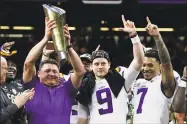  ?? Sue Ogrocki / Associated Press ?? LSU coach Ed Orgeron holds the trophy beside quarterbac­k Joe Burrow, center, and safety Grant Delpit after winning the NCAA College Football Playoff national championsh­ip game against Clemson on Monday in New Orleans. LSU won 42-25.