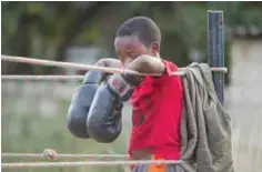  ??  ?? A young boy rests on the ropes after a boxing fight.