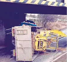  ??  ?? A lorry carrying a digger comes to grief.