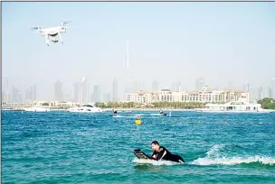  ??  ?? A drone follows a man riding a motorized surfboard with Burj Khalifa, the world’s tallest building, in the distance in Dubai, UAE on June 25. Dubai has begun to allow sporting events again amid the coronaviru­s pandemic and the Dubai Internatio­nal Marine Club hosted a water sports event Thursday to celebrate. (AP)