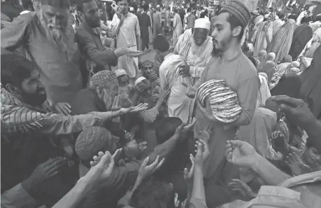  ?? MUHAMMAD SAJJAD/AP FILE ?? A worker distribute­s free traditiona­l roti among needy people at a restaurant in Peshawar, Pakistan, April 16.